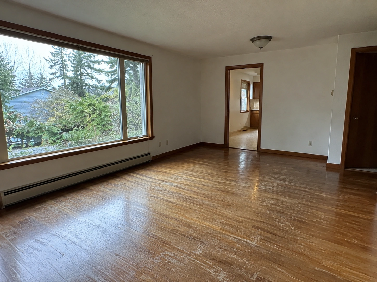 Rental living room with worn flooring and older trim